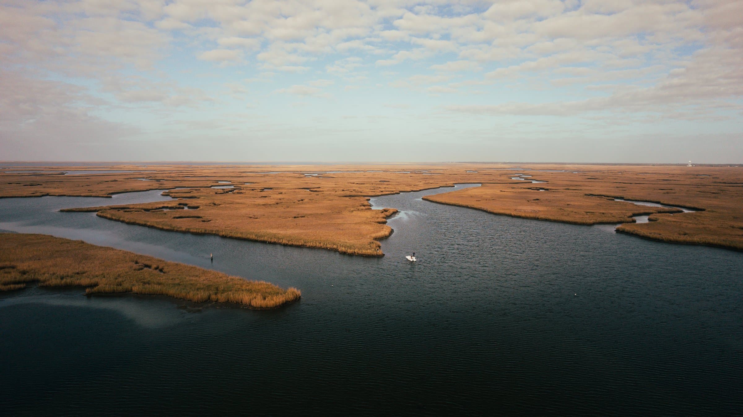 Aerial view of a skiff running through Louisiana marsh channels on a redfish fly fishing trip.